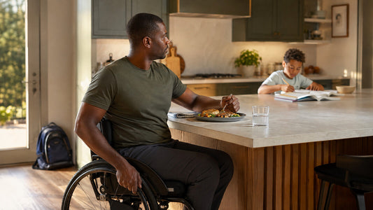 Father using a wheelchair pausing to eat while his child works at the kitchen island